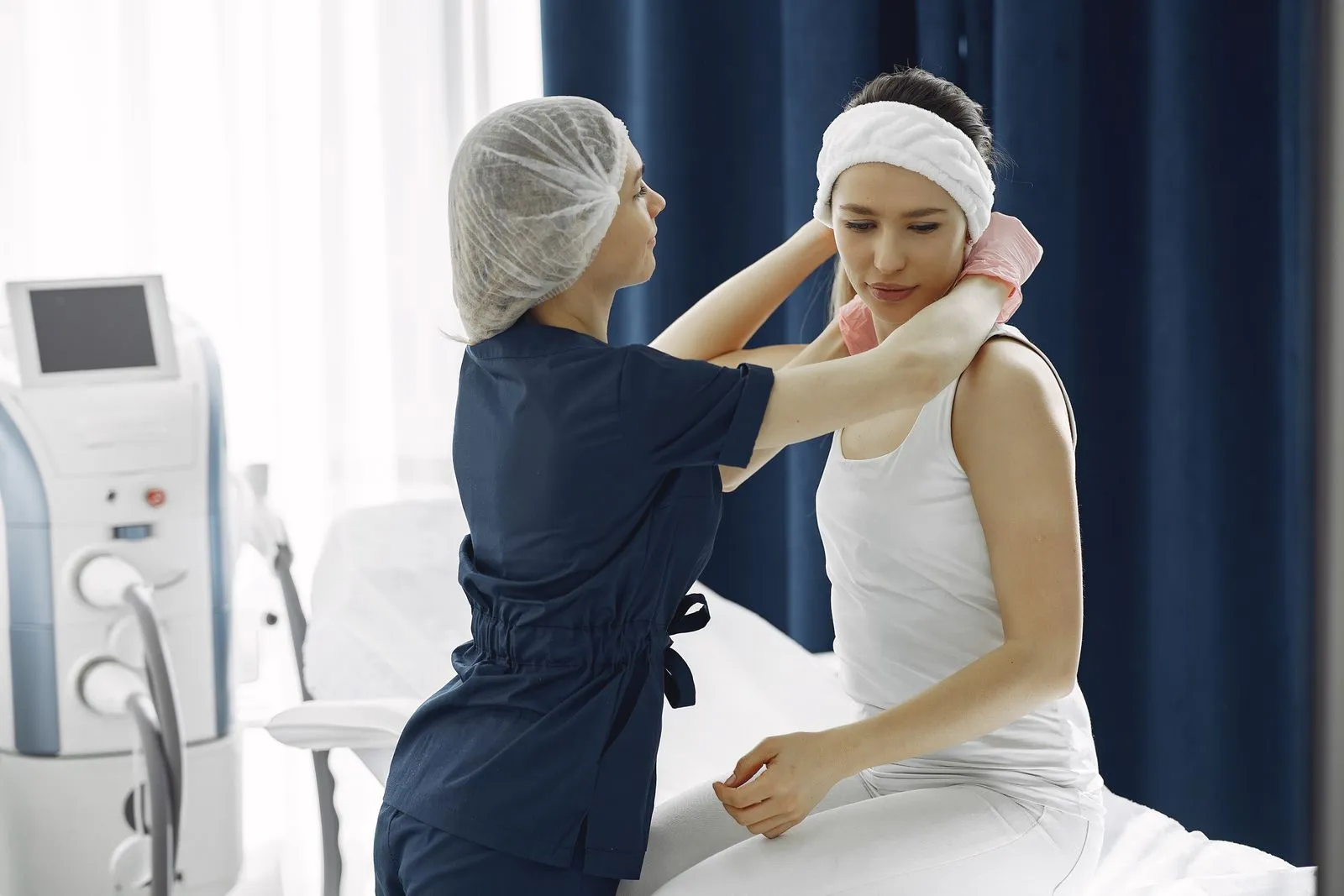 An aesthetic nurse checking a client’s skin before a treatment