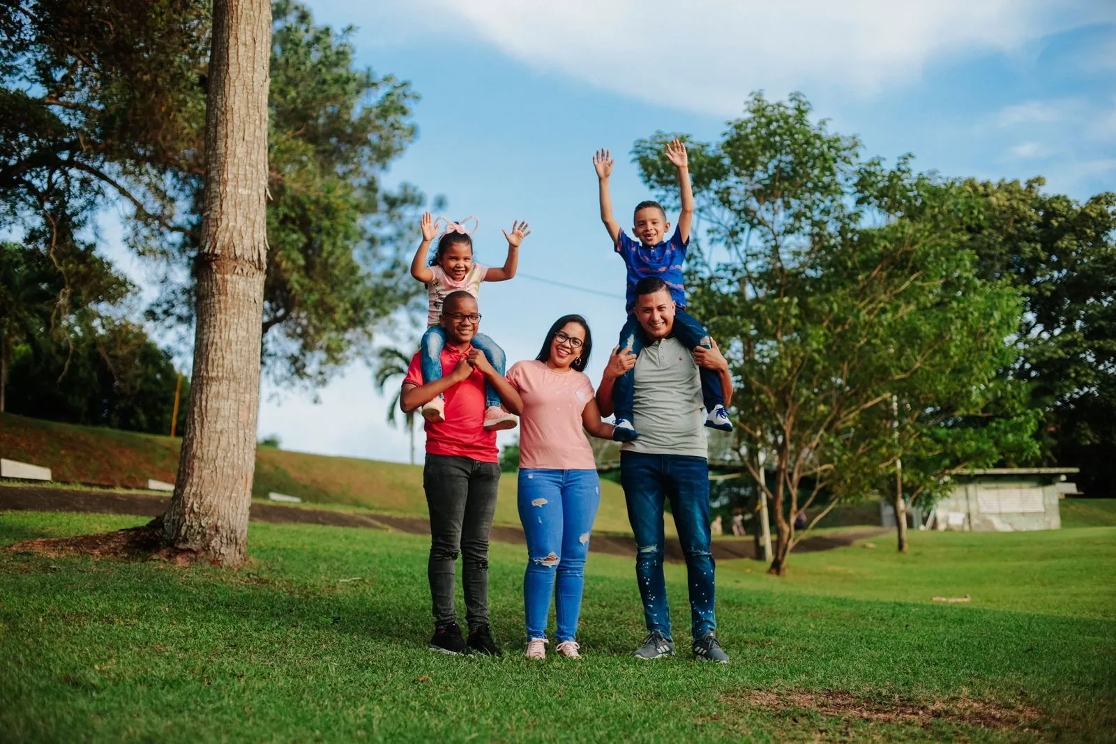 A family of five laughing together in a park