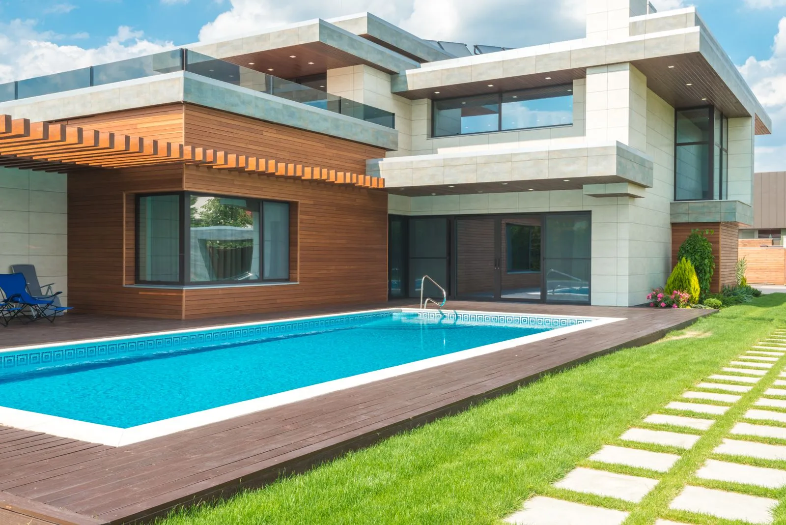 A rectangular pool with wood decking beside a modern house