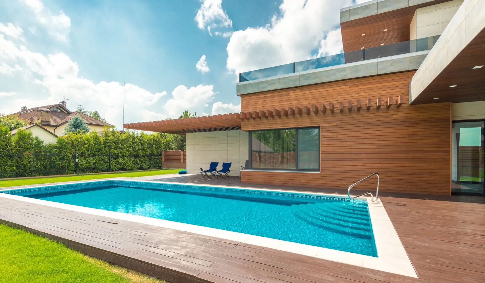 A long pool beside a modern home with a lawn on one side