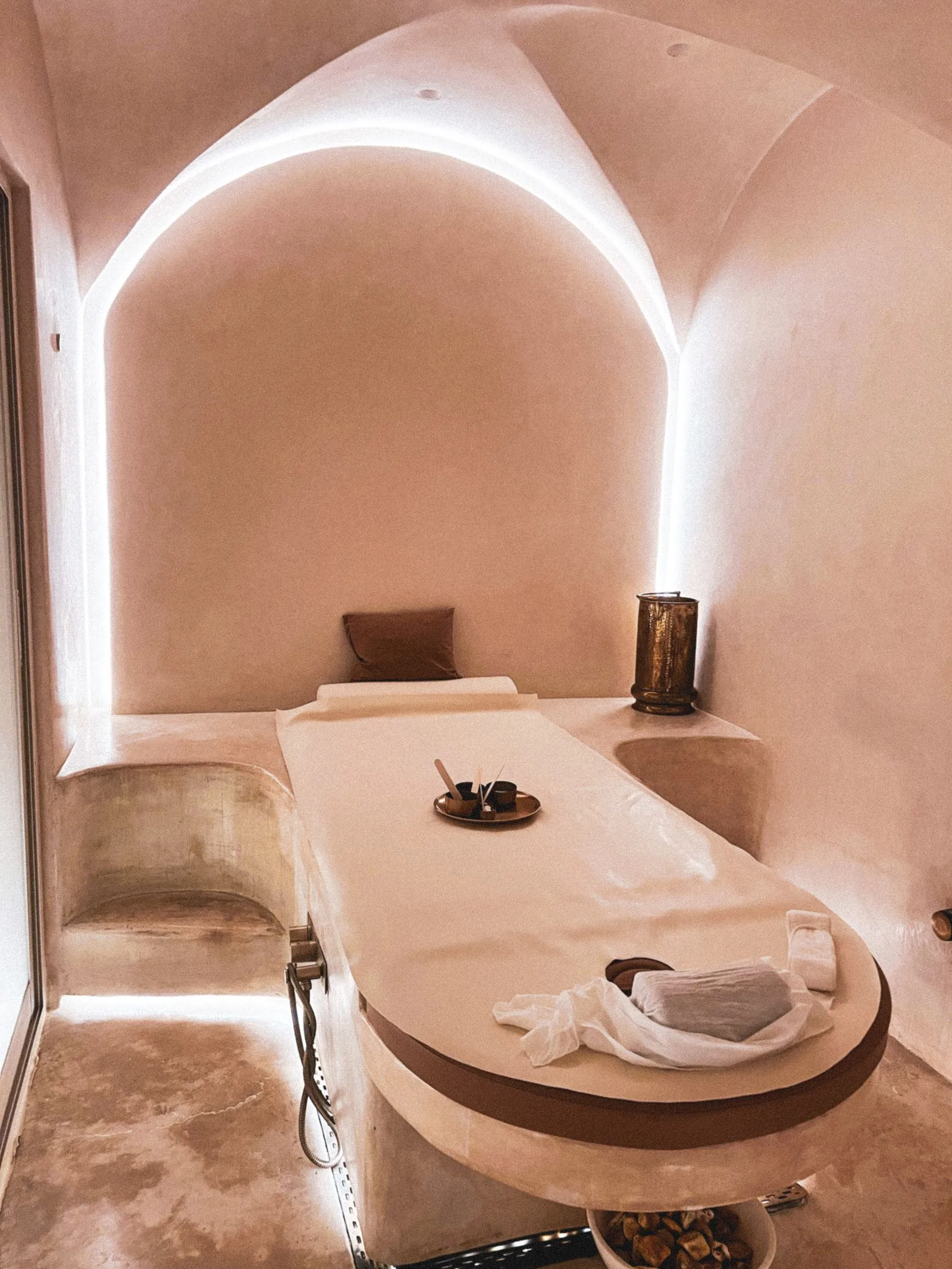 A calm treatment room with an arched ceiling, soft lighting, and a made treatment bed
