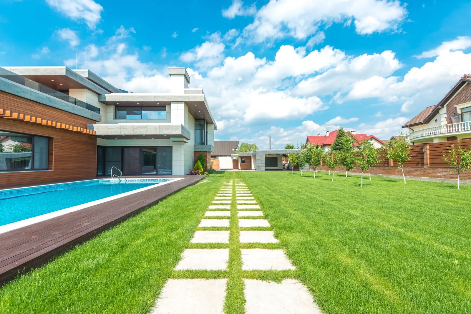 Concrete stepping pavers through a green lawn next to a pool